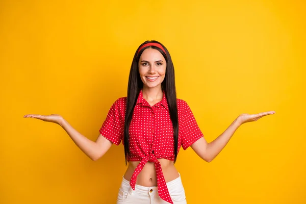 Πορτρέτο του γοητευτικό χαρούμενο κορίτσι κρατώντας στις παλάμες δύο επιλογές vs διαφήμιση απομονώνονται σε φωτεινό κίτρινο χρώμα φόντο — Φωτογραφία Αρχείου