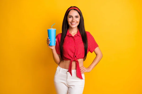Fénykép bájos csinos fiatal lány öltözött piros ing gazdaság kék szóda üveg elszigetelt sárga szín háttér — Stock Fotó