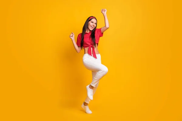 Foto de longitud completa de adorable niña afortunada vestida camisa roja bailando puños ascendentes aislados de color amarillo de fondo —  Fotos de Stock