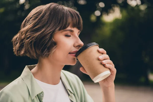 Profil boční pohled portrét atraktivní vysněný dívka pití horké sladké latte nápoj odpočívá na čerstvém vzduchu venku — Stock fotografie