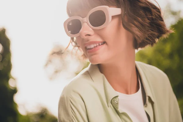 Zdjęcie słodkie marzycielski młoda dama ubrana zielona koszula ciemne okulary spacery uśmiechnięty zewnątrz miejski park — Zdjęcie stockowe