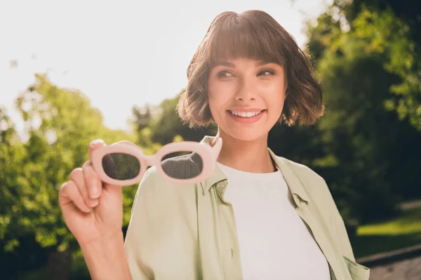 Foto retrato chica joven con el pelo bob mantener gafas de sol sonriendo tener buen humor en verano —  Fotos de Stock