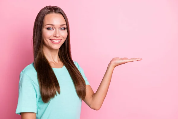 Fotoporträt einer lächelnden Frau, die auf pastellrosa Hintergrund einen leeren Raum auf der Hand hält — Stockfoto