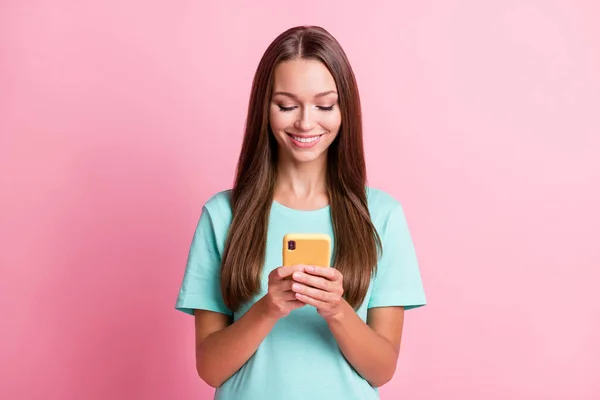 Foto portret van een glimlachende vrouw houden smartphone met behulp van app glimlachen geïsoleerd op pastel roze kleur achtergrond — Stockfoto