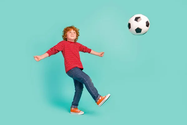 フル長さの写真の面白い小さな男の子遊びサッカーウェアシャツジーンズスニーカー隔離された青の背景 — ストック写真