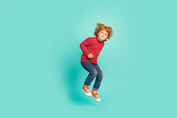 Full tělo foto legrační malý chlapec skok nosit košili džíny tenisky izolované na modrém pozadí — Stock fotografie