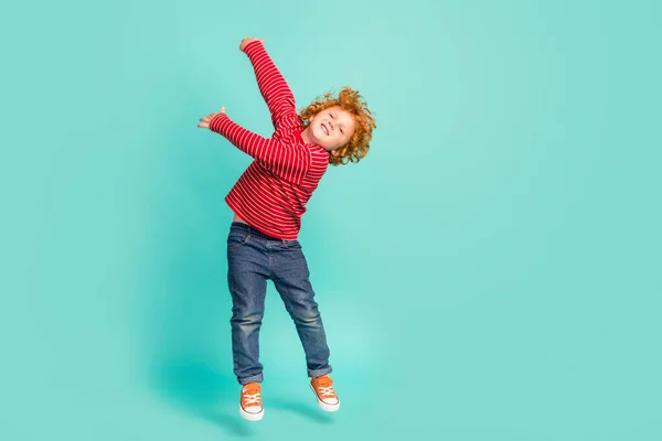 Full tělo foto cool malý chlapec skok nosit tričko džíny tenisky izolované na modrém pozadí — Stock fotografie