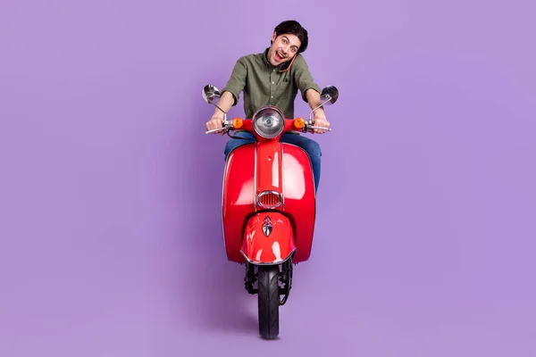 Full length photo of happy positive young man ride bike talk phone smile good mood isolated on violet color background — Stok Foto