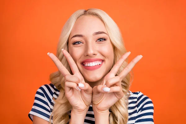 Foto retrato mujer rubia con camiseta rayada feliz mostrando v-signo aislado color naranja brillante fondo —  Fotos de Stock