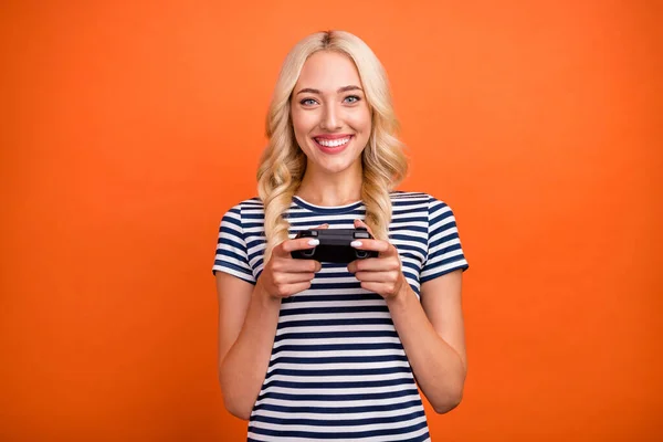 Portret van aantrekkelijke vrolijke meisje met behulp van console spelen web game besteden vrije tijd geïsoleerd over fel oranje kleur achtergrond — Stockfoto