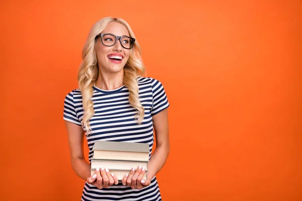 Retrato de cientista menina alegre atraente segurando pilha solução espaço cópia livro isolado sobre fundo de cor laranja brilhante — Fotografia de Stock