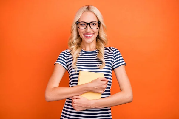Portrét atraktivní veselá dívka objímání zajímavé knihy hobby zábava izolované přes jasně oranžové barvy pozadí — Stock fotografie