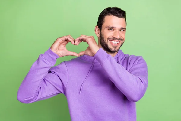 젊은 남성의 행복 한 긍정적 인 미소 사진은 녹색 배경 위에 고립된 가슴 상징 사랑을 보여준다 — 스톡 사진