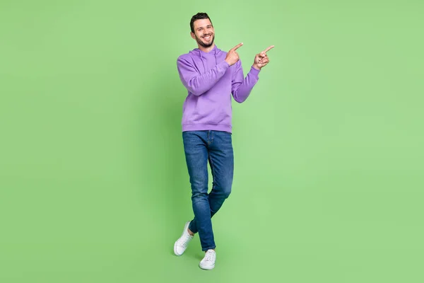 Foto de comprimento total de engraçado millennial morena cara ponto desgaste com capuz jeans tênis isolado no fundo verde — Fotografia de Stock