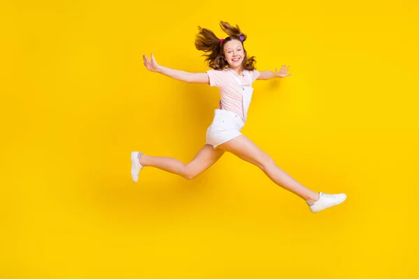 전체 몸길이 사진 학교 여학생 부주의 하게 격리 된 밝은 노란색 배경 위로 뛰어오르는 모습 — 스톡 사진