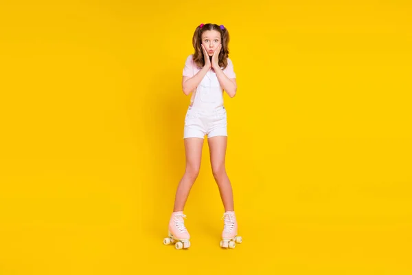 Вид в полный рост на привлекательную ошеломленную девочку, катающуюся на коньках, губы, изолированные на ярко-желтом фоне — стоковое фото