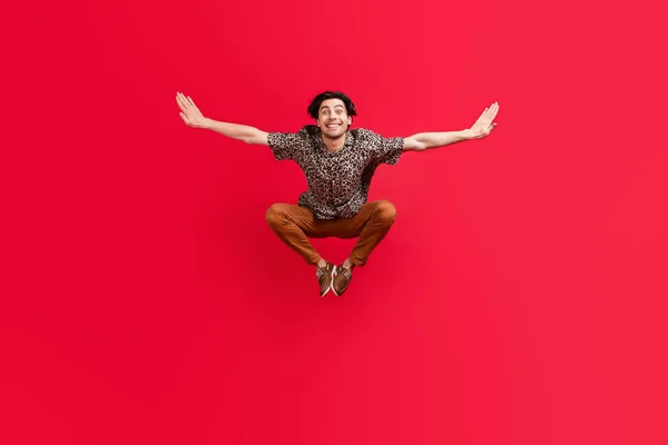 Πλήρης φωτογραφία μεγέθους του νεαρού χαμογελαστού ελκυστική τύπος πηδώντας τα χέρια φτερά που φέρουν ελευθερία που απομονώνονται στο φόντο κόκκινο χρώμα — Φωτογραφία Αρχείου