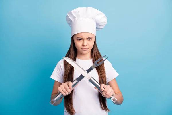 Foto di infelice arrabbiato bruna furiosa bambina tenere coltello forchetta cucina incrociata isolato su sfondo di colore blu — Foto Stock