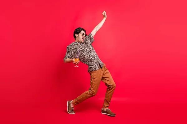 Genç, dikkatsiz, heyecanlı, bağıran adamın tam boy fotoğrafı. Kırmızı arka planda muzaffer bir şekilde izole edilmiş kokteyl dansı içen adam. — Stok fotoğraf