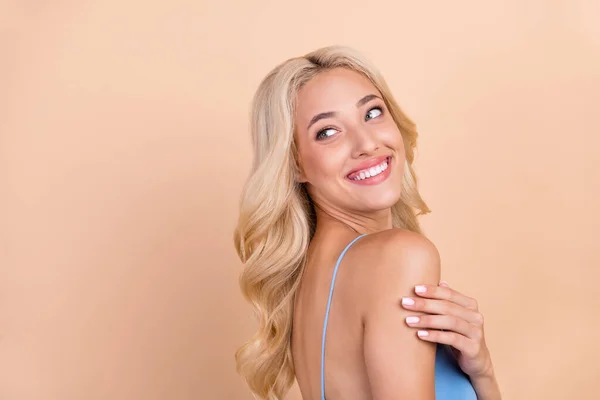 Foto de muito sonhador jovem senhora desgaste azul singlet sorrindo olhando para trás espaço vazio isolado cor bege fundo — Fotografia de Stock