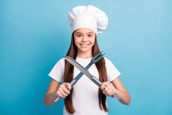 Φωτογραφία του ευτυχισμένου θετικού μικρού κοριτσιού χαμόγελο καλή διάθεση κρατήσει μαγειρικά σκεύη διασταυρώθηκε απομονωμένο σε μπλε φόντο χρώμα — Φωτογραφία Αρχείου