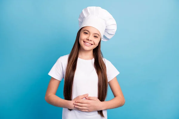 Foto di positivo felice allegra piccola ragazza tenere le mani pancia usura cappello da chef isolato su sfondo di colore blu — Foto Stock