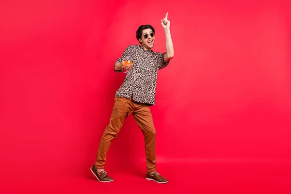 Foto in voller Größe von lächelnd aufgeregt fröhlichen Mann tanzen Zeigefinger Copyspace-Anzeige empfehlen isoliert auf rotem Hintergrund — Stockfoto