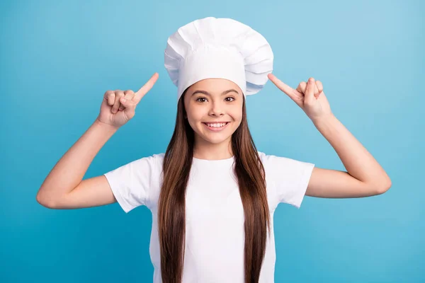 Foto di positivo felice allegra bambina punto dito cappello cucinare cucina isolata su sfondo di colore blu pastello — Foto Stock