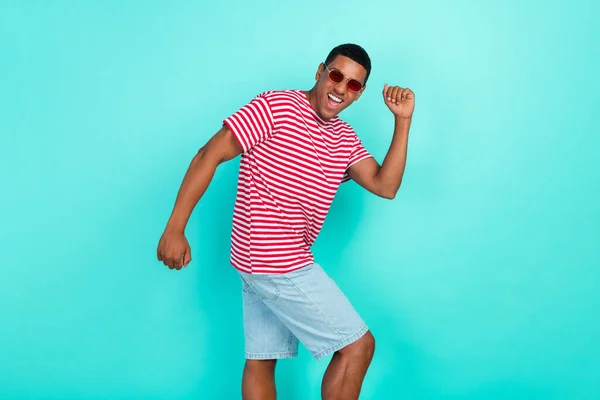 Foto de lindo chico divertido vestido camiseta roja bailando sonriente aislado color turquesa fondo —  Fotos de Stock