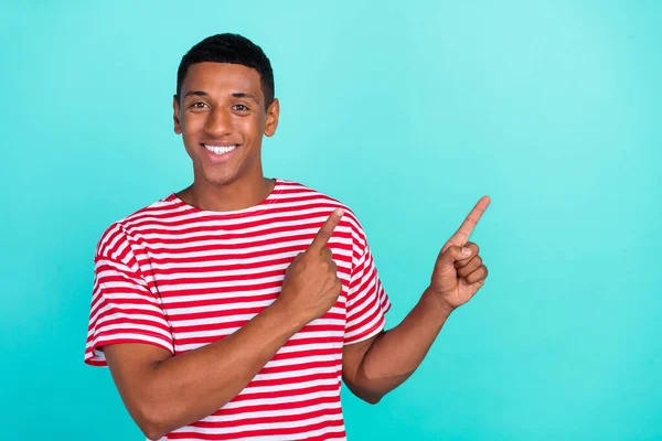 Photo de mignon drôle jeune gars habillé rouge t-shirt pointant les doigts espace vide souriant isolé couleur turquoise fond — Photo