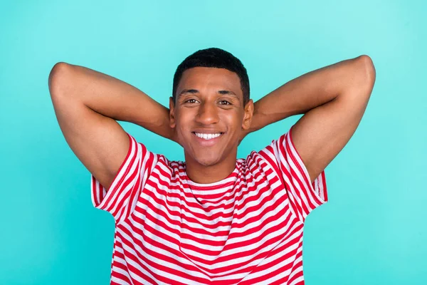 Zdjęcie słodkie atrakcyjny młody człowiek nosić pasiasty t-shirt uśmiechnięte ramiona za głową odizolowany ciemny morski tło — Zdjęcie stockowe