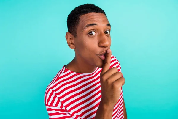 Foto de un joven guapo serio que usa una camiseta a rayas con los labios de los dedos pidiendo mantener el silencio aislado fondo de color verde azulado — Foto de Stock