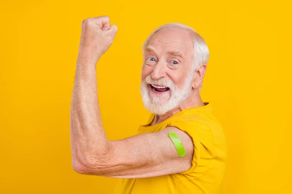 Photo de vieil homme étonné célébrer la vaccination victoire porter t-shirt isolé couleur jaune fond — Photo