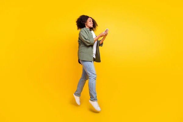 Full längd profil foto av rolig brunett ung plus storlek dam springa skriva telefon bära skjorta jeans skor isolerad på gul bakgrund — Stockfoto
