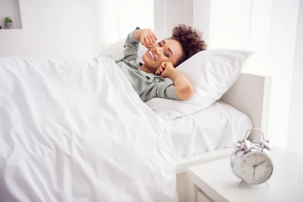 Πορτρέτο της ελκυστική χαρούμενα κυματιστά μαλλιά κορίτσι που βρίσκεται στο κρεβάτι ξυπνώντας υγιές καθεστώς στο σπίτι φως σε εσωτερικούς χώρους — Φωτογραφία Αρχείου