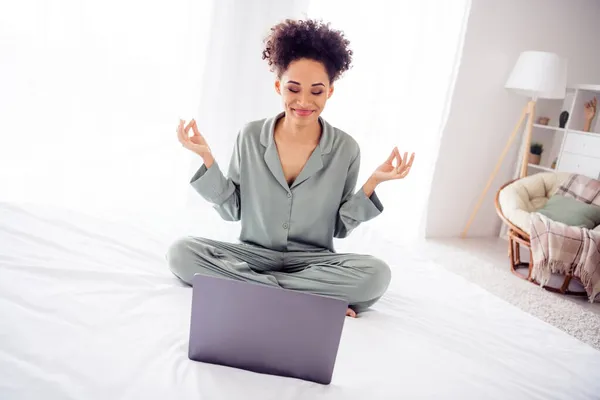 Ritratto di attraente sognante ragazza allegra seduta sul letto con computer portatile meditando a casa luce all'interno — Foto Stock