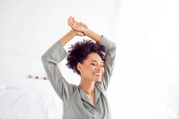 Φωτογραφία από ονειρική θετική χαρούμενη κυρία απολαύσετε το πρωινό τέντωμα σηκώστε τα χέρια φορούν μεταξένια φόρεμα στο σπίτι φως υπνοδωμάτιο σε εσωτερικούς χώρους — Φωτογραφία Αρχείου