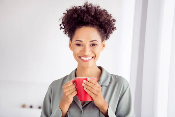 Fénykép fiatal vidám afro lány ébredés jó hangulat ital finom kávé tea latte viselni selymes pizsama beltérben — Stock Fotó