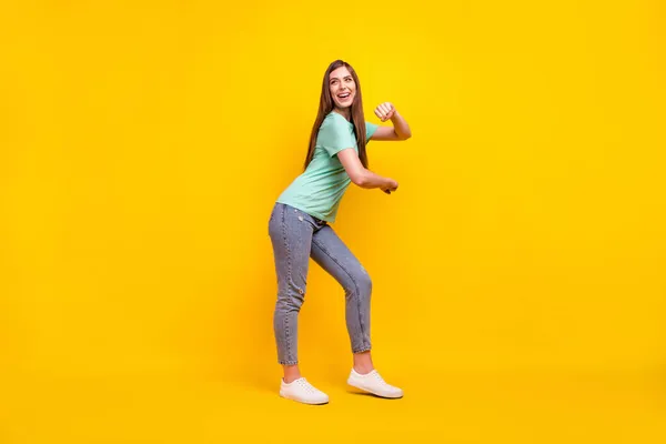 Perfil de corpo inteiro foto de engraçado morena penteado jovem senhora dança desgaste t-shirt jeans tênis isolado no fundo amarelo — Fotografia de Stock