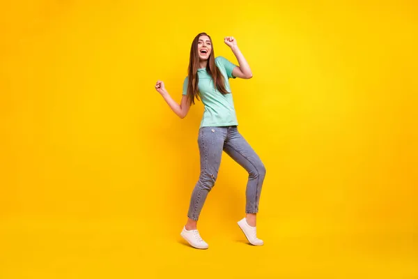 Uzun boylu, esmer, güzel saçlı, genç bayan dansçısının fotoğrafı. Sarı arka planda izole edilmiş t-shirt kotları giyin. — Stok fotoğraf