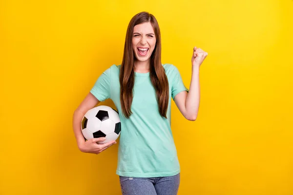 Foto di hooray bruna acconciatura giovane signora tenere palla usura teal t-shirt isolato su sfondo di colore giallo — Foto Stock