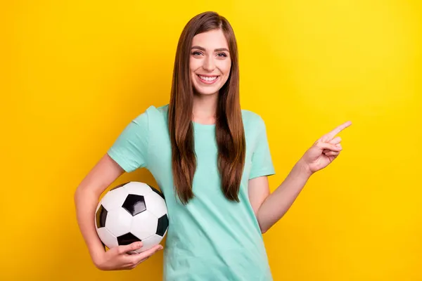 Photo of cool brunetka hairdo millennial lady point puste miejsce trzymać piłkę nosić ciemny t-shirt izolowane na żółtym tle kolor — Zdjęcie stockowe