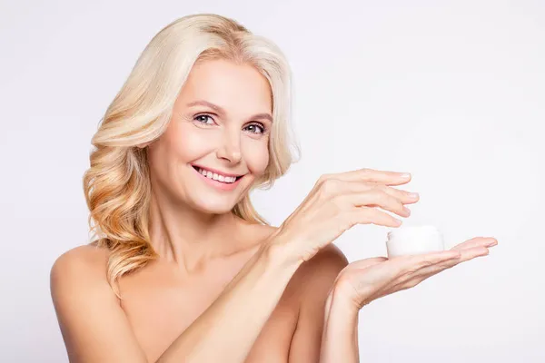 Ritratto di attraente donna allegra che tiene su palmo utilizzando crema maschera balsamo collagene facciale isolato su sfondo di colore bianco — Foto Stock