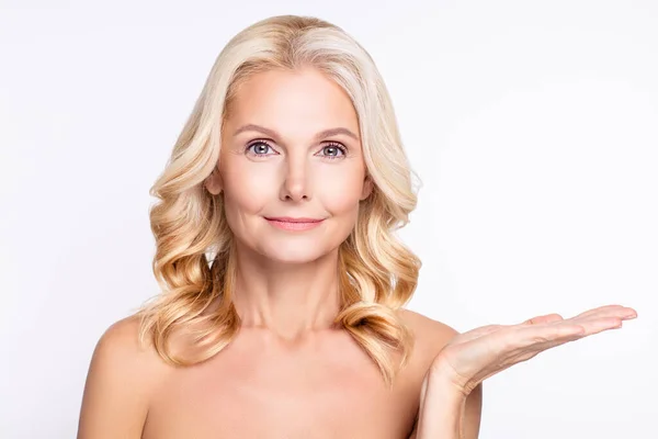Retrato de atractiva anciana sana mujer de pelo gris sosteniendo en copia de la palma espacio vacío cosmético aislado sobre fondo de color blanco — Foto de Stock
