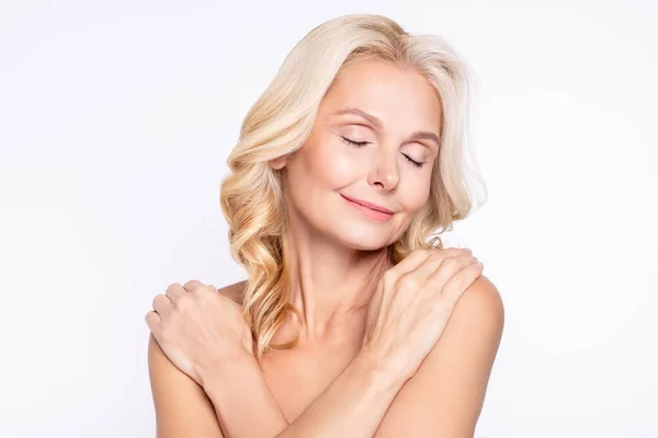 Portrait of attractive dreamy healthy grey-haired woman hugging shoulders after shower gel peeling isolated over white color background — Stock Photo, Image