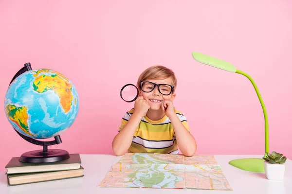Fotografie malého veselého chlapce držet ruce loupe geografie lekce brýle cool izolované na růžovém pozadí — Stock fotografie