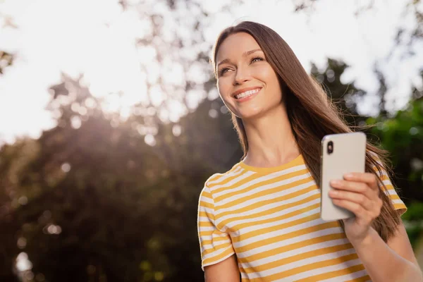 Photo portrait femme passer du temps libre dans le parc d'été en gardant smartphone souriant rêveur — Photo