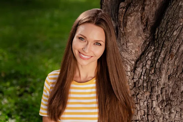 Фотопортрет счастливая улыбающаяся женщина в полосатой футболке отдыхает в зеленом парке в выходные дни — стоковое фото