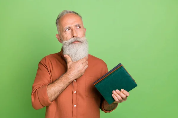 Foto de hombre anciano pensativo mirada reflexiva espacio vacío libro literatura aislada sobre fondo de color verde — Foto de Stock