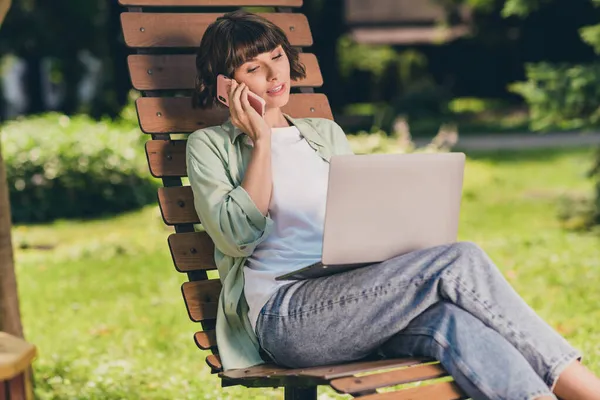 Portrét atraktivní zaostřené dívky sedící v křesle pomocí notebooku volající partner mluvit diskutovat o projektu venku — Stock fotografie